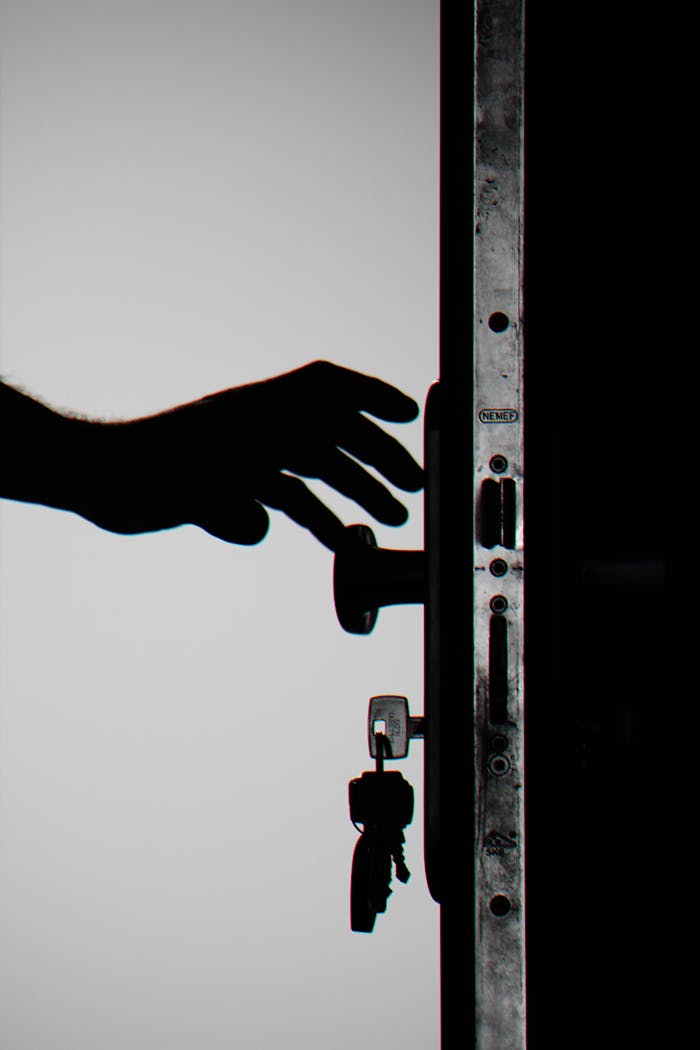 Home Silhouette of a hand about to open a door with keys in lock, symbolizing security.